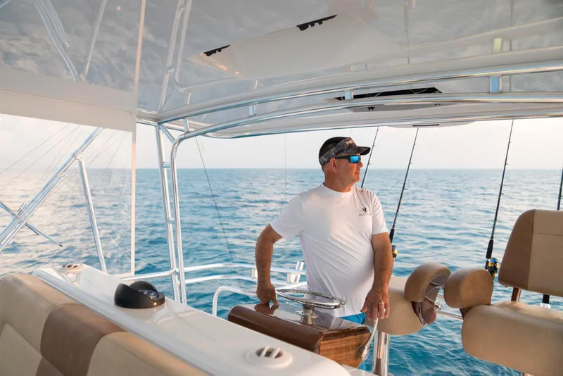 Slide: The Image of Man steering 2023 Bertram 61 Convertible yacht on open sea. - 16