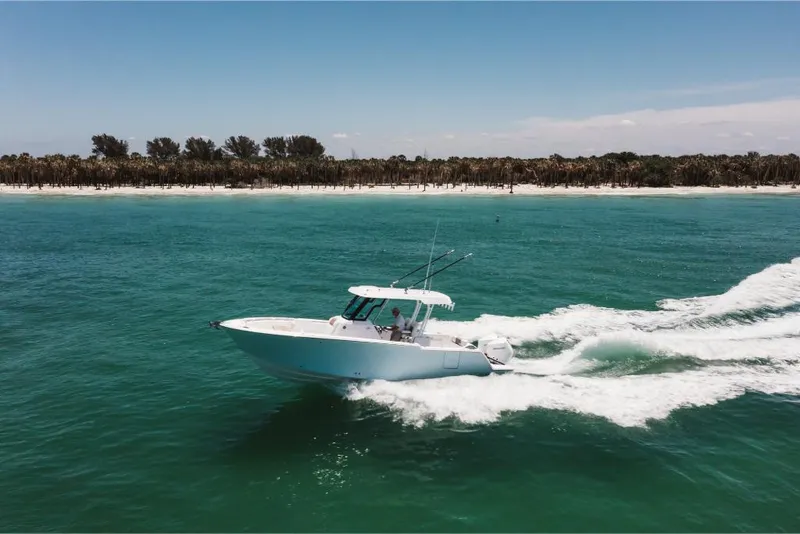 Slide: The Image of 2023 Bertram 28CC cruising on turquoise waters near a sandy beach. - 10