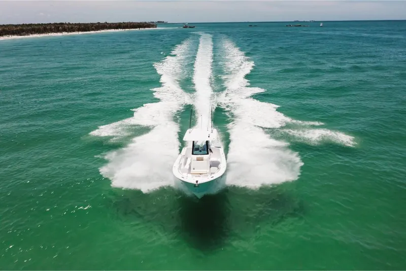 Slide: The Image of 2023 Bertram 28CC boat cruising on clear turquoise waters. - 11