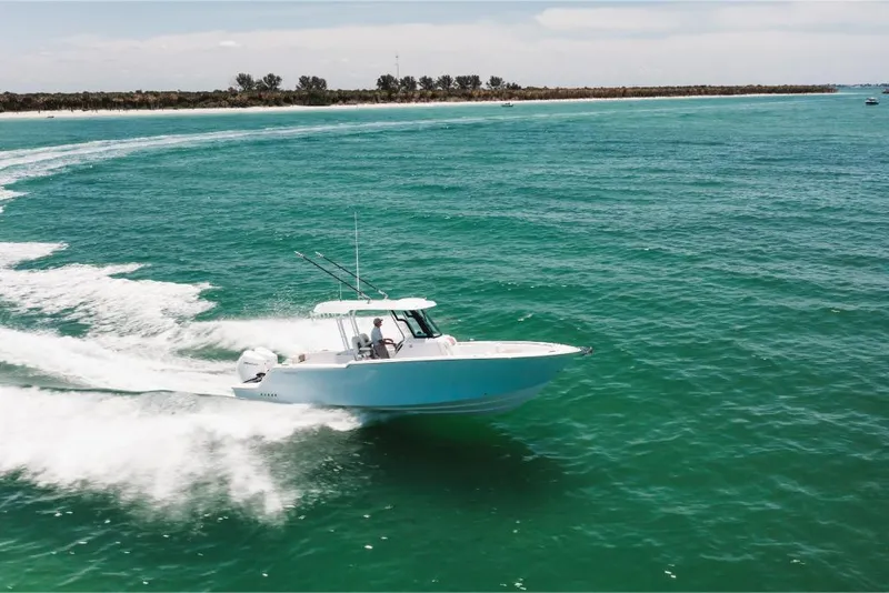 Slide: The Image of 2023 Bertram 28CC boat cruising on clear blue water near a sandy shoreline. - 13