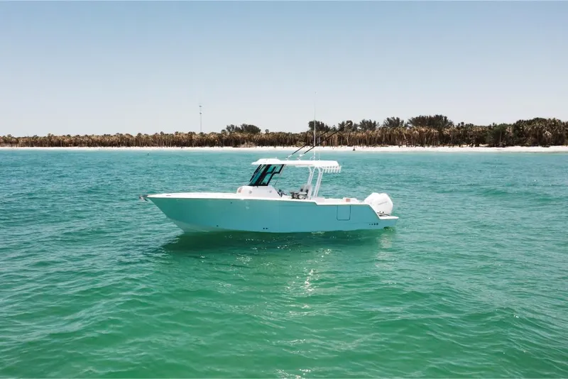 Slide: The Image of 2023 Bertram 28CC boat on clear turquoise water near a sandy shoreline. - 3