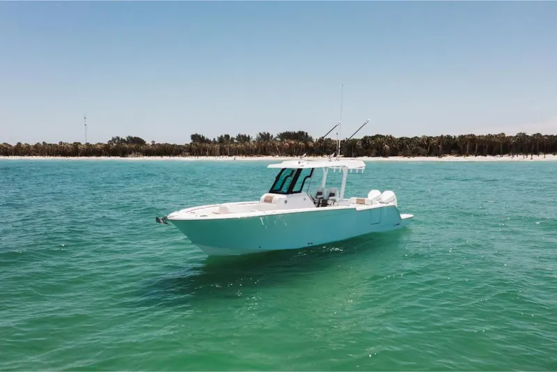 Slide: The Image of 2023 Bertram 28CC boat on clear turquoise water near a sandy shoreline. - 4