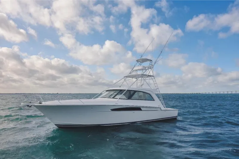 Slide: The Image of 2023 Bertram 50 Sport yacht cruising on open water under a partly cloudy sky. - 1