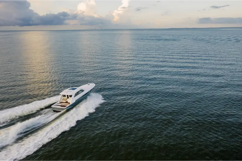Slide: The Image of 2023 Bertram 50 Sport yacht cruising on open water at sunset. - 16