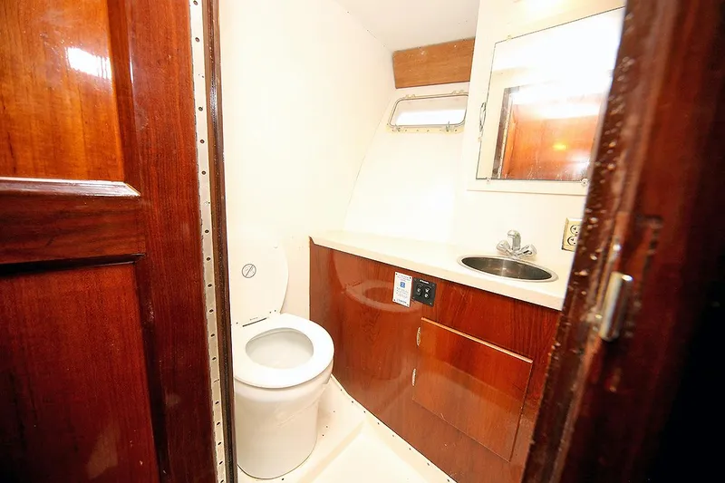 Slide: The Image of 1971 Hatteras 45 Convertible yacht bathroom with wooden cabinetry and white fixtures. - 23