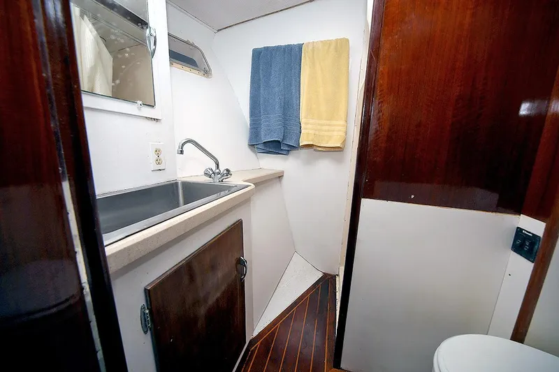 Slide: The Image of 1971 Hatteras 45 Convertible yacht bathroom with sink, towels, and wooden cabinetry. - 28