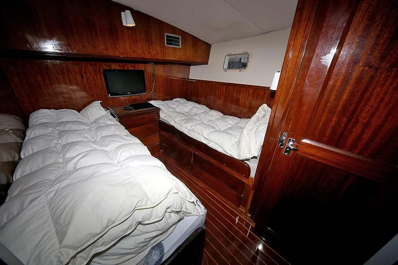 Slide: The Image of 1971 Hatteras 45 Convertible cabin with twin beds, wooden interior, and a small TV. - 30
