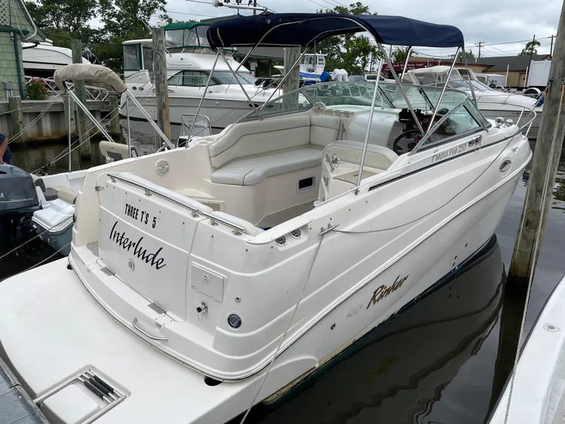 The Image of 2005 Rinker 250 Fiesta Vee boat docked, featuring white exterior and blue canopy. - 0
