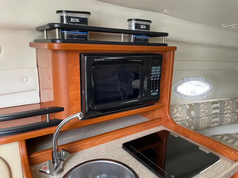 Slide: The Image of 2005 Rinker 250 Fiesta Vee boat interior with microwave, sink, and stove. - 11