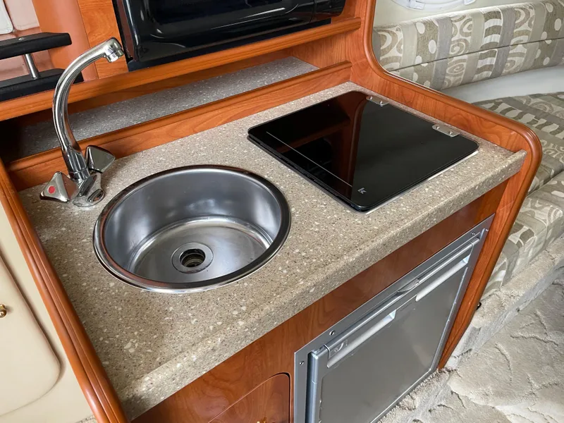 Slide: The Image of 2005 Rinker 250 Fiesta Vee boat kitchenette with sink, stove, and mini-fridge. - 13