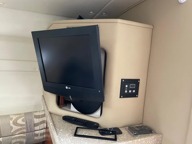 Slide: The Image of 2005 Rinker 250 Fiesta Vee cabin with LG TV and remote controls. - 16