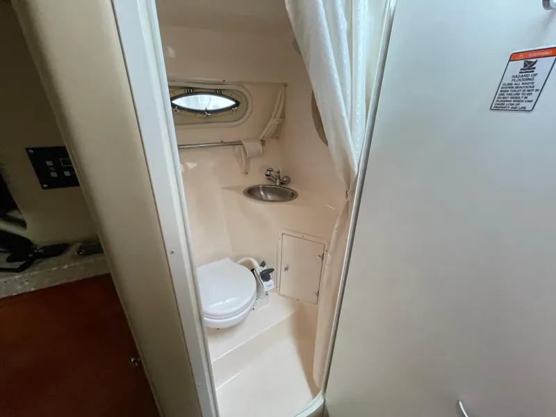 Slide: The Image of 2005 Rinker 250 Fiesta Vee boat bathroom with toilet, sink, and porthole window. - 18