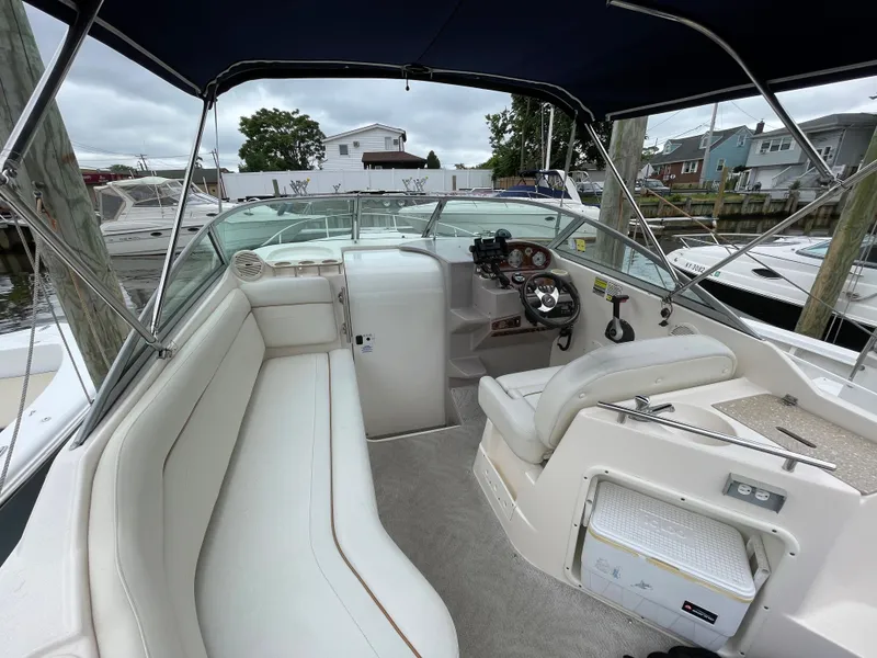 Slide: The Image of 2005 Rinker 250 Fiesta Vee boat interior with white seating and steering console. - 2