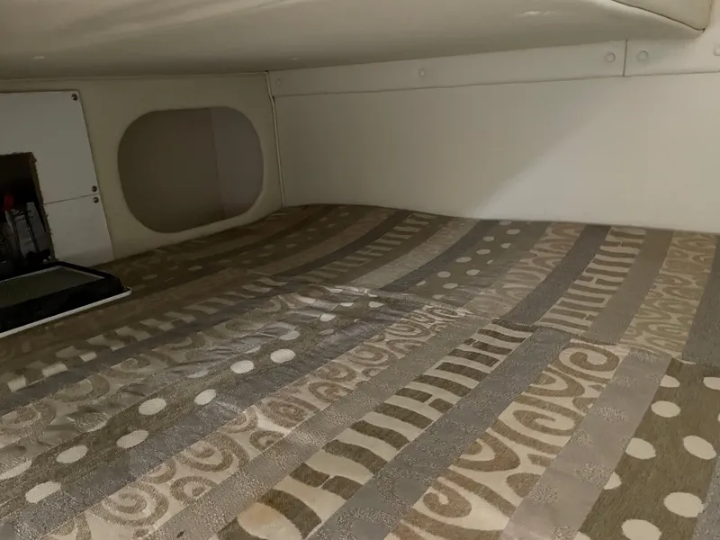 Slide: The Image of 2005 Rinker 250 Fiesta Vee cabin interior with patterned bedding and storage compartment. - 22