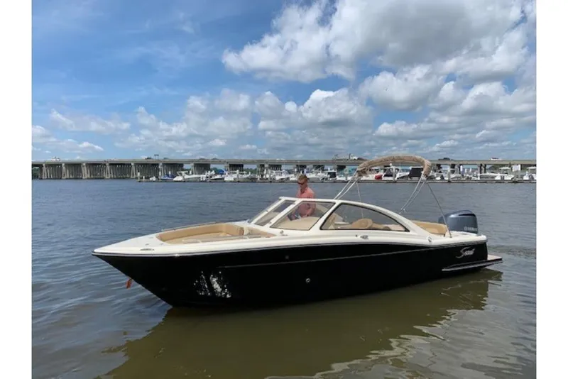 Slide: The Image of 2023 Scout 240 Dorado boat on water with bridge and marina in background. - 2