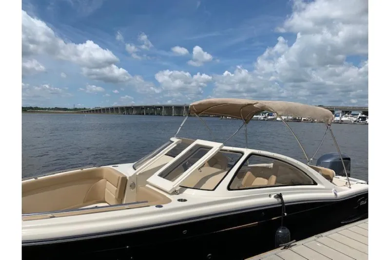 Slide: The Image of 2023 Scout 240 Dorado boat docked by a scenic waterfront with a bridge in the background. - 5