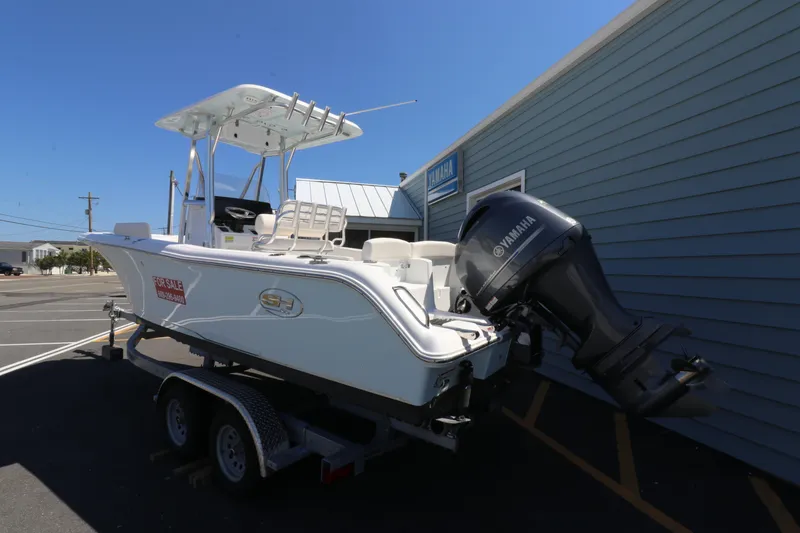 Slide: The Image of 2021 Sea Hunt Ultra 234 boat with Yamaha engine on trailer, parked beside building. - 2