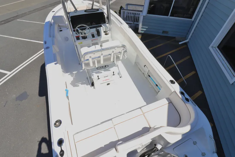 Slide: The Image of 2021 Sea Hunt Ultra 234 boat interior with seating and console, docked near a building. - 3
