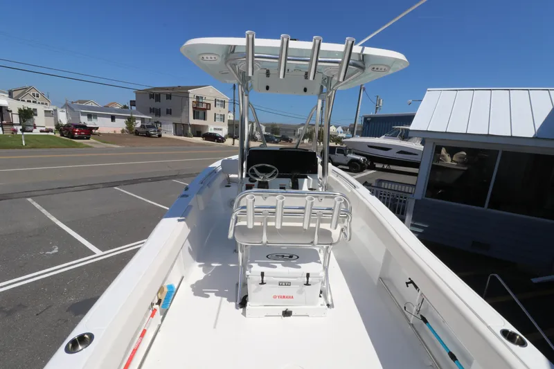 Slide: The Image of 2021 Sea Hunt Ultra 234 boat with T-top and seating, parked in a coastal area. - 4