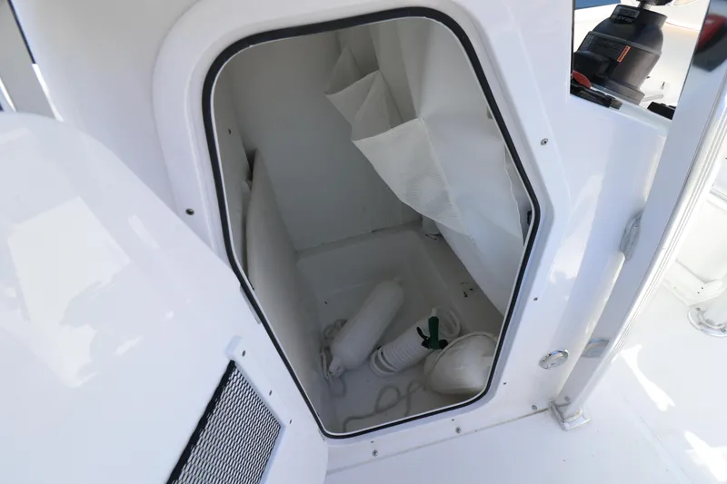 Slide: The Image of Storage compartment on a 2021 Sea Hunt Ultra 234 boat, featuring white interior and equipment. - 8
