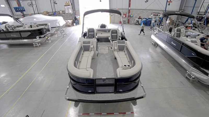 Slide: The Image of 2023 Barletta C24UC pontoon boat in a showroom, showcasing spacious seating and modern design. - 2