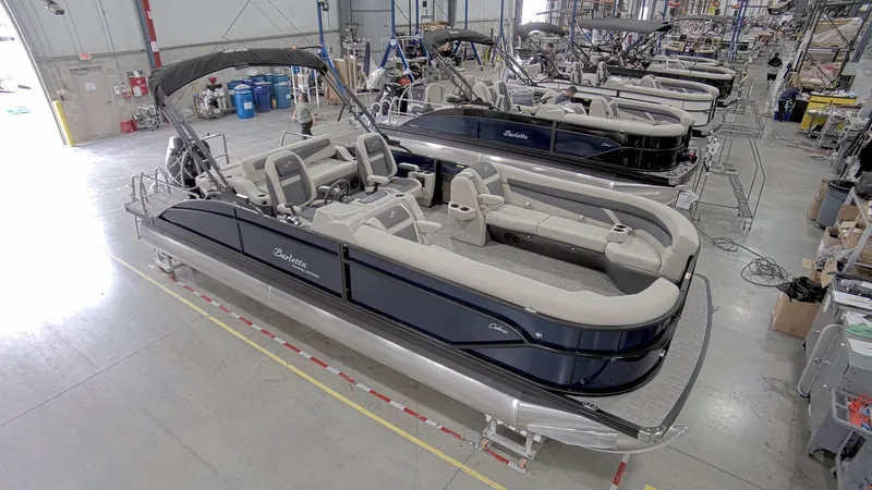 Slide: The Image of 2023 Barletta C24UC pontoon boat in a manufacturing facility, showcasing sleek design and spacious seating. - 5
