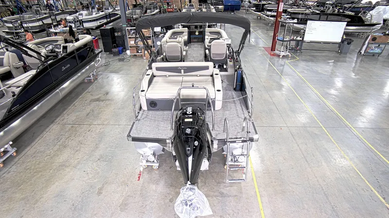 Slide: The Image of 2023 Barletta C24UC pontoon boat in a showroom, rear view with seating and motor. - 7