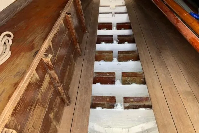Slide: The Image of Interior of a 1919 Herreshoff S Class sailboat showing wooden floorboards and structural beams. - 16