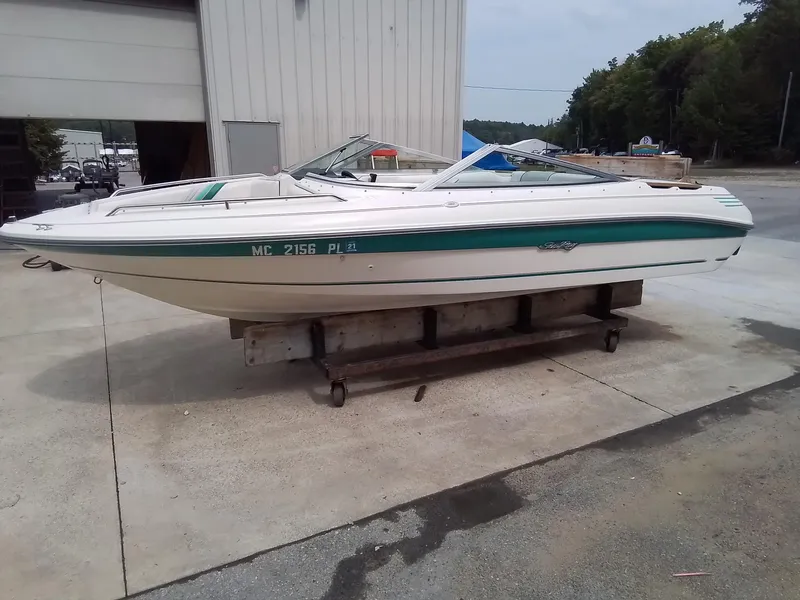 Slide: The Image of 1993 Sea Ray 180 BR boat on a stand, white with green stripe, outdoor setting. - 4