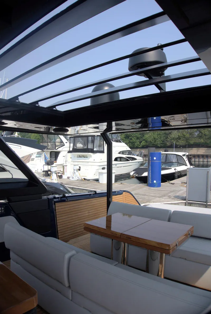 Slide: The Image of 2024 Cranchi A46 yacht interior with sleek seating and modern design at a marina. - 23