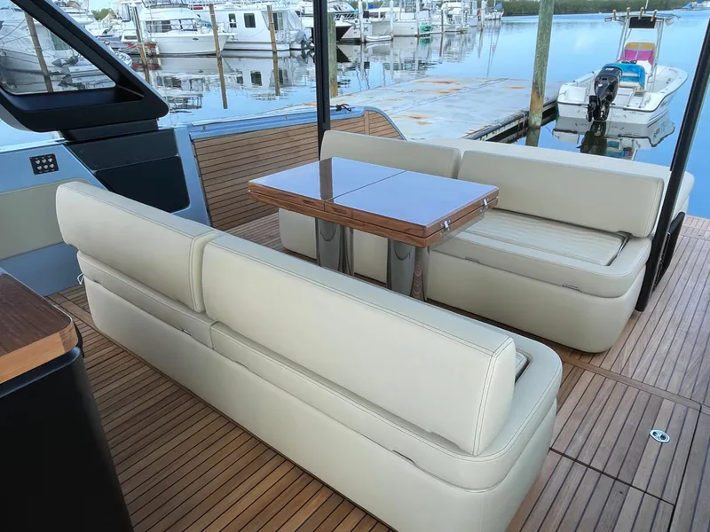 Slide: The Image of 2023 Cranchi A46 yacht with beige seating and wooden table at marina. - 26