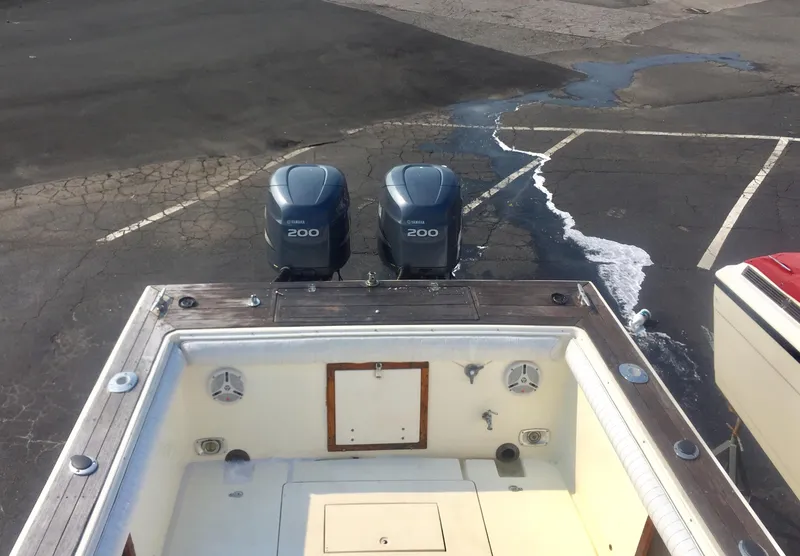 Slide: The Image of 1991 Mako 260 Walk Around boat with twin 200 HP engines in a parking lot. - 10