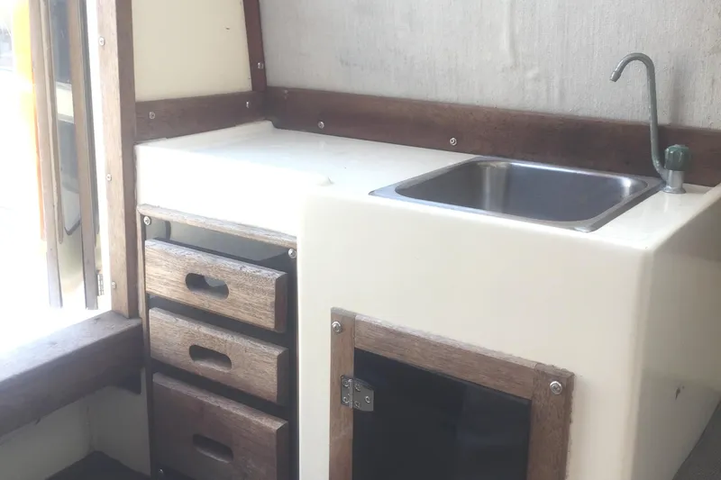 Slide: The Image of Compact kitchen area in a 1991 Mako 260 Walk Around boat with sink and storage drawers. - 17