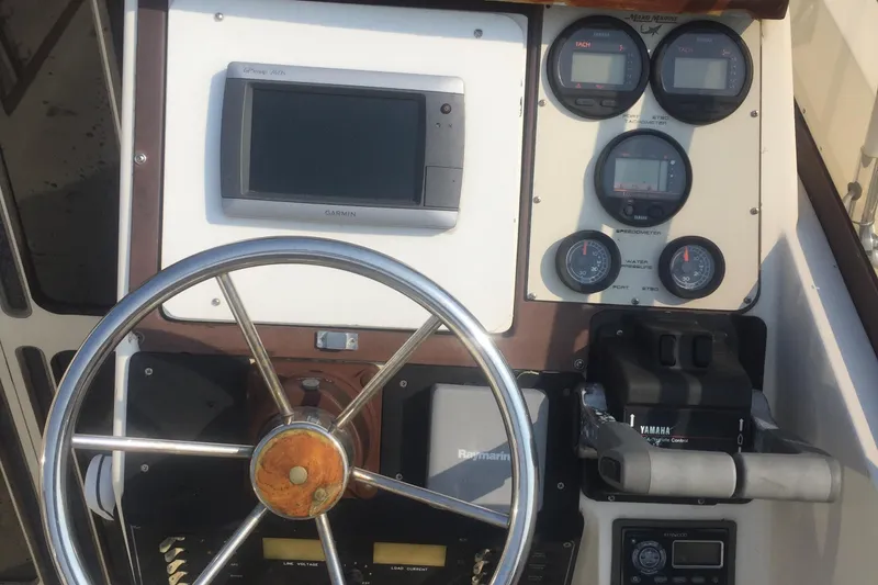 Slide: The Image of 1991 Mako 260 Walk Around boat dashboard with steering wheel and gauges. - 8