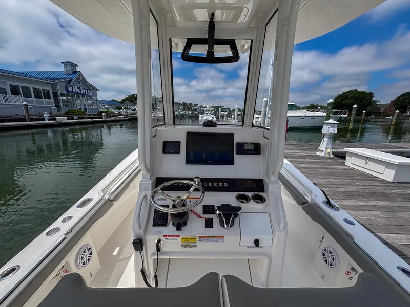 Slide: The Image of 2025 Regulator 23 boat cockpit with steering wheel and control panel at marina. - 10