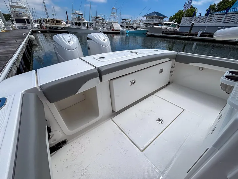 Slide: The Image of 2025 Regulator 23 boat interior at marina, featuring storage compartments and twin engines. - 14