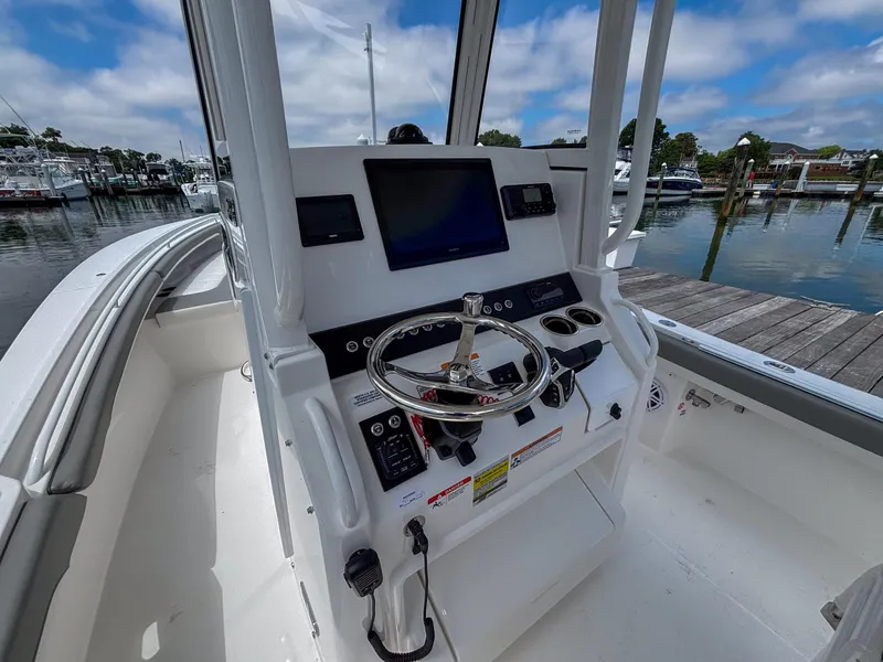 Slide: The Image of 2025 Regulator 23 boat console with steering wheel and navigation screen at marina. - 15