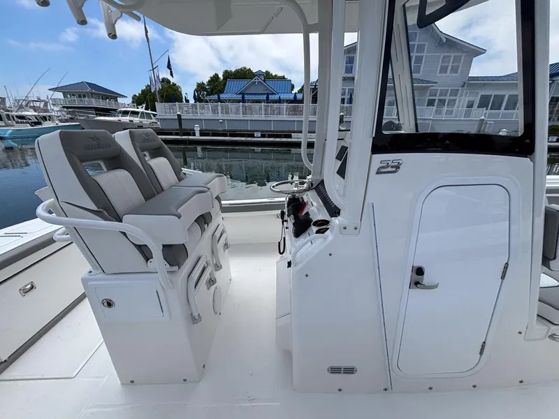 Slide: The Image of 2025 Regulator 23 boat interior with dual seats and helm, docked at marina. - 20