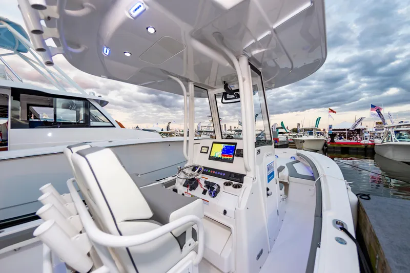 Slide: The Image of 2025 Regulator 23 boat interior with modern console at marina, under cloudy sky. - 24