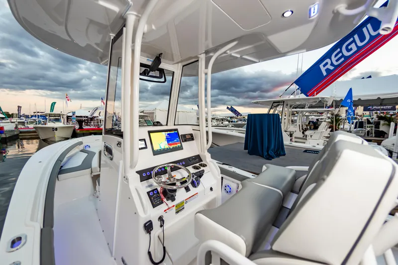 Slide: The Image of 2025 Regulator 23 boat interior at marina, featuring modern dashboard and seating. - 26
