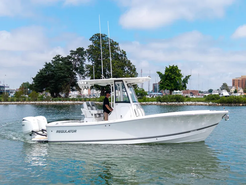 Slide: The Image of 2025 Regulator 23 boat cruising on a calm lake with trees in the background. - 3