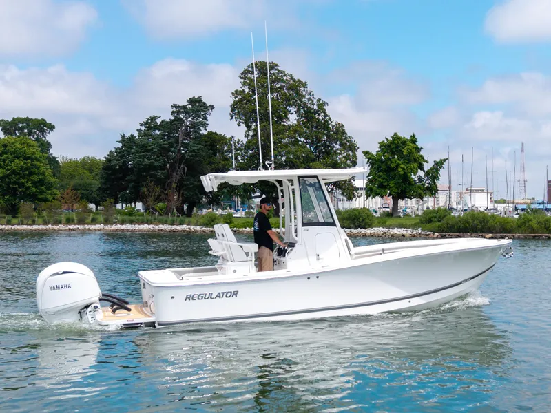 Slide: The Image of 2025 Regulator 23 boat cruising on a calm lake with trees in the background. - 4