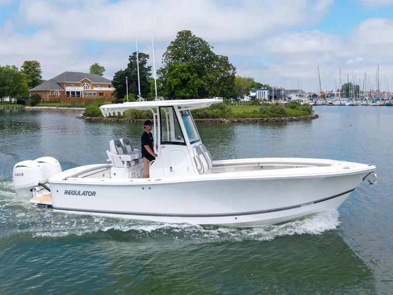 Slide: The Image of 2025 Regulator 23 boat cruising on a calm lake near a marina. - 5