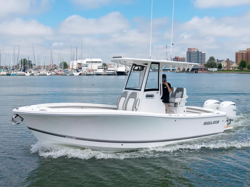 Slide: The Image of 2025 Regulator 23 boat cruising in a marina with cityscape background. - 7