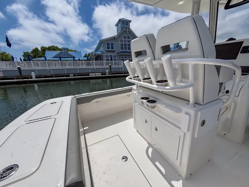 Slide: The Image of 2025 Regulator 23 boat interior with seating and rod holders, docked near a waterfront building. - 9