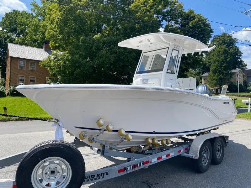 Slide: The Image of 2025 Sea Fox 228 Commander boat on trailer, parked on a sunny street. - 2