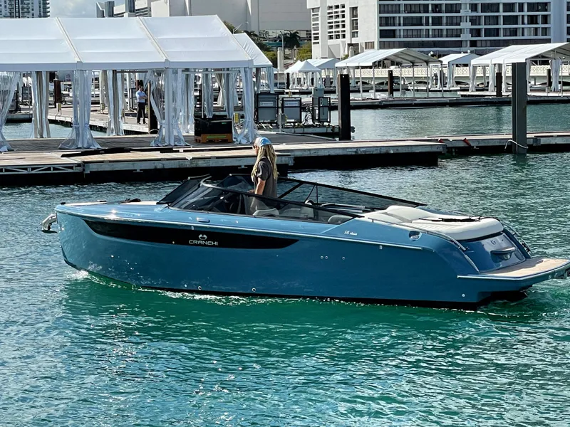 Slide: The Image of 2022 Cranchi 26 Classic boat cruising near a marina with white canopies. - 1