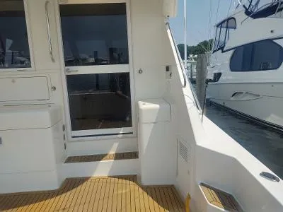 Slide: The Image of 2003 Riviera 48 Conv yacht deck with teak flooring and marina view. - 10