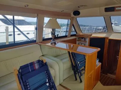 Slide: The Image of Interior of 2003 Riviera 48 Conv yacht with seating, table, and windows overlooking marina. - 16