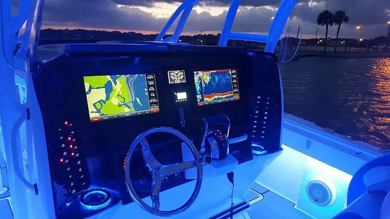 Slide: The Image of 2023 Nor-Tech 392 Super Fish boat dashboard with illuminated navigation screens at dusk. - 3